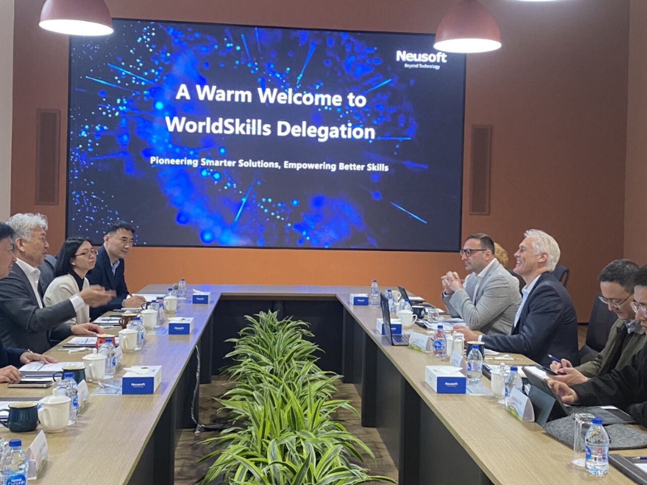 Representatives from Neusoft and WorldSkills International at a meeting in a board room.
